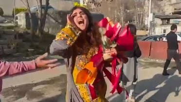 This image grab from a UGC video posted outside of Iran on March 15, 2023, shows Iranian activist and journalist Sepideh Qolian walking with a bouquet of flowers outside the walls of Evin prison in Tehran, following her release. (AFP)