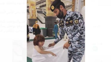 رجل أمن يساعد طفلاً في المسجد الحرام