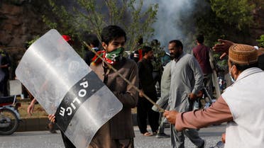 A supporter of former Pakistani Prime Minister Imran Khan, walks with a riot shield used by the police, during a clash outside the federal judicial complex in Islamabad, Pakistan March 18, 2023. (Reuters)