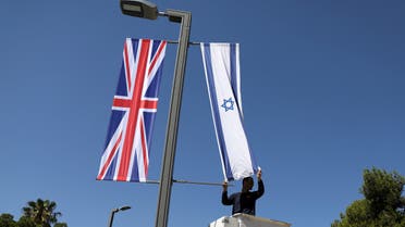 A Jerusalem municipality worker hangs an Israeli flag next to the British flag, the Union Jack, as he stands on a platform near Israel's presidential residence in Jerusalem ahead of the upcoming visit of Britain's Prince William, June 25, 2018. (File photo: Reuters)