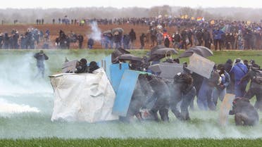 Protesters, surrounded by tear gas, clash with riot mobile gendarmes during a demonstration called by the collective “Bassines non merci”, the environmental movement “Les Soulevements de la Terre” and the French trade union ‘Confederation paysanne’ to protest against the construction of a new water reserve for agricultural irrigation, in Sainte-Soline, central-western France, on March 25, 2023. (AFP)