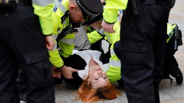 One of the activists from the climate change protest group Extinction Rebellion (XR), that glued her hands to the reception desk of headquarters of Royal Dutch Shell, a multinational oil and gas company, is carried away by police officers while she is arrested, in central London on April 13, 2022, following a protest as part of a series of actions aiming to stop the fossil fuel economy. (AFP)