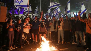 Israeli protesters chant in front of a burning fire at a demonstration against Israeli Prime Minister Benjamin Netanyahu and his nationalist coalition government's plan for judicial overhaul, in Tel Aviv, Israel, March 27, 2023. (Reuters)