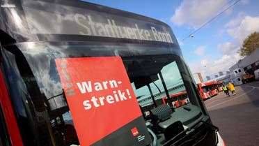People walk near a bus with a notice behind the windshield at a storage facility during a nationwide strike called by the German trade union Verdi over a wage dispute, in Bonn, Germany, March 27, 2023. The notice reads: Warning strike! REUTERS/Wolfgang Rattay