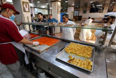 A worker carves for a customer portions of Kunafa, a popular Arabic dessert, off a tray at a shop in Kuwait City on the second day of the Muslim holy fasting month of Ramadan on April 3, 2022. (File photo: AFP)