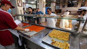 A worker carves for a customer portions of Kunafa, a popular Arabic dessert, off a tray at a shop in Kuwait City on the second day of the Muslim holy fasting month of Ramadan on April 3, 2022. (File photo: AFP)