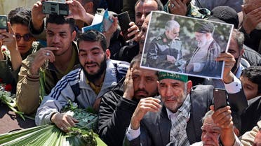 A man holds a sign depicting slain Iranian military commander Qasem Soleimani (L) and Supreme Leader Ali Khamenei during the funeral procession for two IRGC officers killed by Israel in Syria, held in Tehran on April 4, 2023. (AFP)