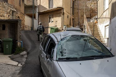 An Israeli police bomb disposal unit member walks past a damaged car in the aftermath of rocket fire launched from Lebanon and intercepted by Israel in its northern town of Fassuta on April 6, 2023. (AFP)