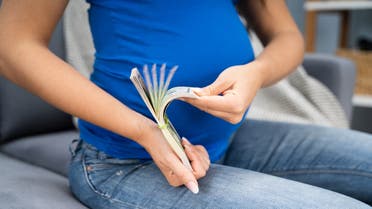 Pregnant Woman Counting US Dollar Bills stock photo