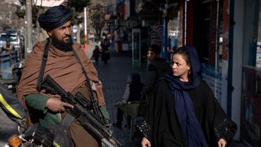 FILE - A Taliban fighter stands guard as a woman walks past in Kabul, Afghanistan, on Dec. 26, 2022. The United Nations' human rights chief on Tuesday Dec. 27, 2022 decried increasing restrictions on women's rights in Afg