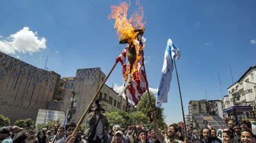 Men hold up make-shift Israeli and US flags set on fire during a rally marking Quds Day (Jerusalem Day), a commemorative day held annually on the last Friday of the Muslim fasting month of Ramadan by an initiative started by late Iranian revolutionary leader Ruhollah Khomeini, in Tehran on April 14, 2023. (AFP)