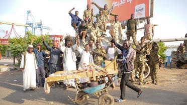 People cheer around Sudanese army soldiers, loyal to army chief Abdel Fattah al-Burhan, manning a position in the Red Sea city of Port Sudan, on April 20, 2023. (AFP)