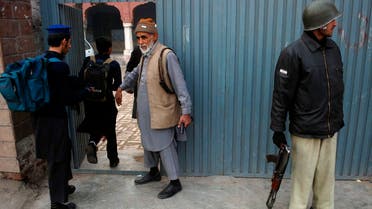 Students walk past an entrance as a policeman (R) and a staff member stand guard outside a school  in Peshawar, Pakistan. (File photo: Reuters) 