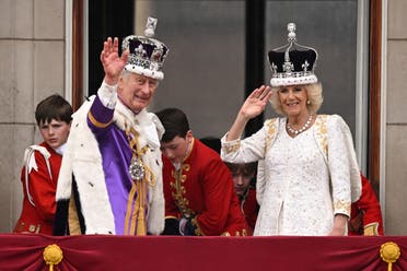 Britain's King Charles III wearing the Imperial state Crown, and Britain's Queen Camilla wearing a modified version of Queen Mary's Crown wave from the Buckingham Palace balcony after viewing the Royal Air Force fly-past in central London on May 6, 2023, after their coronations. (AFP)