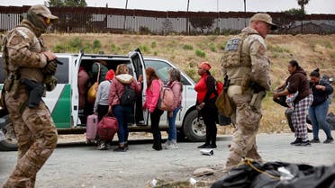 Customs and Border Protection officers walk as immigrants enter a vehicle to be transported from a makeshift camp between border walls, between the U.S. and Mexico, on May 13, 2023 in San Diego, California. (AFP)