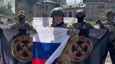 This video grab taken from a handout footage posted on May 20, 2023 on the Telegram account of the press service of Concord -- a company linked to the chief of Russian mercenary group Wagner, Yevgeny Prigozhin -- shows Yevgeny Prigozhin holding a Russian national flag in front of his soldiers holding Wagner Group's flags in Bakhmut, amid the Russian invasion of Ukraine. (AFP)
