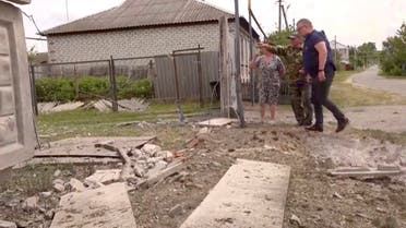 This image taken from a video shows people indicating a damaged building in the Belgorod region, Russia, Monday, May 22, 2023. Russian troops and security forces fought for a second day Tuesday against an alleged cross-border raid that Moscow blamed on Ukrainian military saboteurs but which Kyiv portrayed as an uprising against the Kremlin by Russian partisans. Vyacheslav Gladkov, governor of the Belgorod region on the Ukraine border, said forces continued to sweep the rural area around the town of Graivoron, where the alleged attack on Monday took place. (AP Photo)