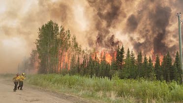 Firefighters retreat as flames approach, amid the Grizzly Wildfire Complex, in East Prairie Metis Settlement, Alberta, Canada May 19, 2023 in this still image obtained from social media video. (Reuters)