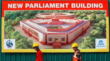 Construction workers walk past a hoarding featuring India's new parliament building outside its construction site in New Delhi, India, December 10, 2020. (Reuters)