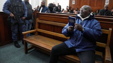 Rwandan genocide suspect Fulgence Kayishema holds up a Christian book, as he appears in the Cape Town Magistrates Court, in Cape Town, South Africa May 26, 2023. REUTERS/Nic Bothma