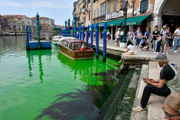 People look at Venice's historical Grand Canal as a patch of phosphorescent green liquid spreads in it, Sunday, May 28, 2023. (AP)