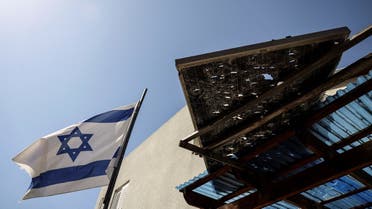 An Israeli national flag is seen next to a damaged part of a roof following rockets that were launched from the Gaza Strip, in Sderot, Israel May 10, 2023. (Reuters)