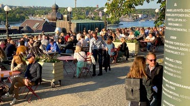 People enjoy drinks and snacks in the evening sun on a terrace overlooking Stockholm, 2023. (AP)