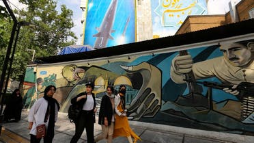 Women walk along a mural painting behind which appears a giant billboard bearing a picture of the ‘Fattah’ hypersonic missile, in Tehran on July 7, 2023. (AFP)