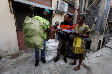 A recyclable waste collector weighs a sack of plastic containers submitted by Fatimoh Adeosun, a parent of a student of My Dream Stead, a low-cost school that accepts recyclable waste as payment, in Ajegunle, Lagos, Nigeria May 19, 2023. (REUTERS)