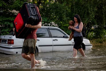 Local residents carry their personal belongings on a flooded street, after the Nova Kakhovka dam breached, amid Russia's attack on Ukraine, in Kherson, Ukraine June 6, 2023. (Reuters)
