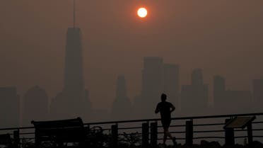 A man runs in front of the sun rising over the lower Manhattan skyline in Jersey City, N.J., Thursday, June 8, 2023. Intense Canadian wildfires are blanketing the northeastern U.S. in a dystopian haze, turning the air