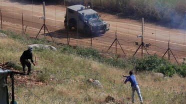 Hezbollah supporters marking the Liberation Day the 23rd anniversary of Israel's withdrawal from southern Lebanon in May 25, 2000, throw stones at an Israeli armored vehicle, on the Lebanese side of the Lebanese-Israeli border in the southern village of Kfar Kila, Thursday, May 25, 2023. (AP)