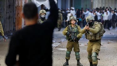 مغربی کنارے میں 19 نومبر 2022 کو اسرائیلی فوجی فلسطینی پر بندوق تانے ہوئے ہیں۔