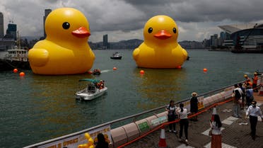 People take photos of an art installation, dubbed Double Ducks by Dutch artist Florentijn Hofman, seen at Victoria Harbour, in Hong Kong, China June 9, 2023. (Reuters)