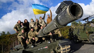 Ukrainian personnel pose with a flag on top of a Challenger 2 tank during a training at Bovington Camp, near Wool in southwestern Britain, February 22, 2023. (Reuters)