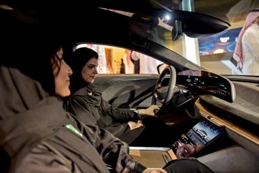 A picture taken on July 14, 2022, ahead of a visit by the United States' president to Saudi Arabia, shows hostesses in a car manufactured by US electric vehicle maker Lucid Group at the KSA Green Transition Journey exhibition in the Red Sea port of Jeddah. (AFP)