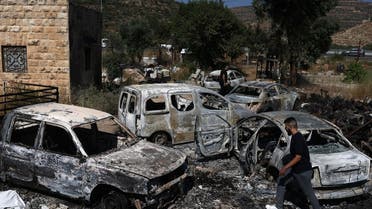 A man walks amidst burnt cars, reportedly set ablaze by Israeli settlers, in the area of in al-Lubban al-Sharqiya in the occupied West Bank on June 21, 2023. (AFP)