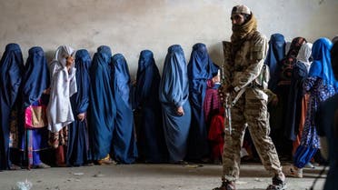A Taliban fighter stands guard as women wait to receive food rations distributed by a humanitarian aid group, in Kabul, Afghanistan, Tuesday, May 23, 2023. (File photo: AP)