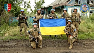 Ukrainian servicemen of the 35th Separate Brigade of Marines pose for a photograph with the Ukrainian flag in the liberated village of Storozheve, in Dontesk region, Ukraine, in the still image taken from a social media video released on June 12, 2023. (Reuters)