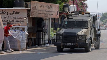 A Palestinian man throws stone at an armoured vehicle during an Israeli military operation in the occupied West Bank city of Jenin, on July 3, 2023. (AFP)