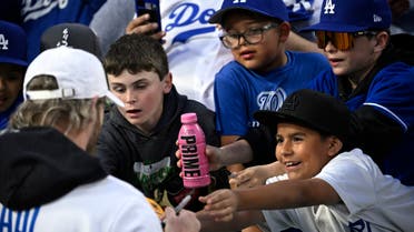 A child holds a PRIME hydration drink while trying to get the autograph of Logan Paul prior to a baseball game between the Los Angeles Dodgers and the Arizona Diamondbacks Friday, March 31, 2023, in Los Angeles. (AP Photo/Mark J. Terrill)