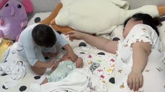 ماں کے سوتے ہوئے کم سن بچے کی چھوٹی بہن کو سلانے کی کوشش:ویڈیو