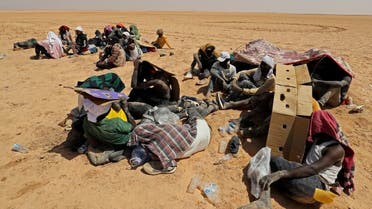 Migrants from sub-Saharan African countries who claim to have been abandoned in the desert by Tunisian authorities without water or shelter, sit in an uninhabited area near Libya's border town of Al-Assah on July 16, 2023. (AFP)