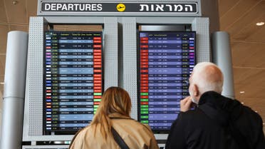 Passengers look at the monitor displaying delayed flights at Ben Gurion airport, near Tel Aviv, Israel, Monday, March 27, 2023. Israeli Airports Authority says flights out of main international airport have been grounded following strike cal. Israel's largest trade union group launched a strike across a broad swath of sectors, joining a surging protest movement against Prime Minister Benjamin Netanyahu's plan to overhaul the judiciary. (AP Photo/Oren Ziv)