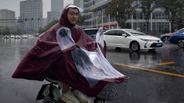 A man rides an electric scooter during heavy rain in Beijing, China, on July 22, 2023. (Reuters) 