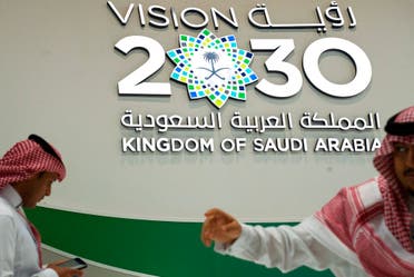 In this Sept. 10, 2019, file photo, men walk past a Vision 2030 display at a stand about Saudi Arabia during the World Energy Congress in Abu Dhabi, United Arab Emirates. (File photo: AP)