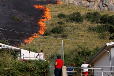 Residents look at flames burning in Capaci, near Palermo, in Sicily, southern Italy, Wednesday, July 26, 2023. (AP)
