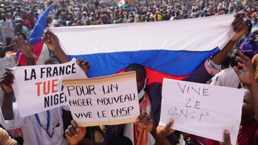 Nigeriens holding a Russian flag and placards participate in a march called by supporters of coup leader Gen. Abdourahmane Tchiani in Niamey, Niger, Sunday, July 30, 2023. (AP)