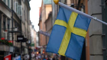 A Swedish flag hangs outside a store on a busy street as visitors walk past in the background in the old town of Stockholm, Sweden, July 14, 2023. (File photo: Reuters)