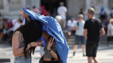 People use a piece of clothing to hide from the sun, during a heatwave in Milan, Italy August 21, 2023. (Reuters)